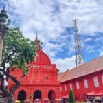 Colorful heritage church in Melaka, Malaysia, with historic architecture and vibrant red exterior, surrounded by lush trees and sky, showcasing Melaka’s rich cultural history and colonial influence.