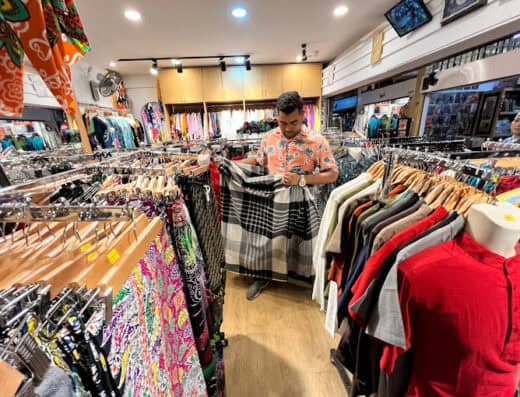 Brightly lit clothing store with racks of colorful garments and a man shopping, showcasing trendy apparel and vibrant fashion options at Onalulu.