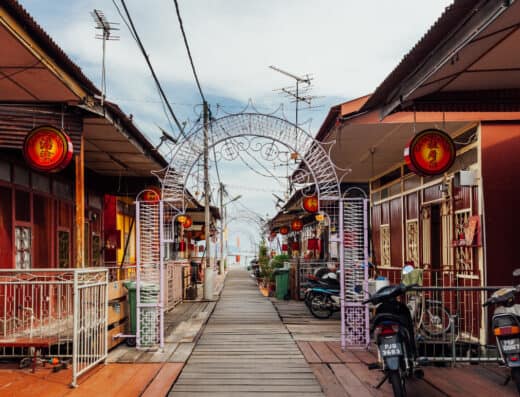 Traditional Asian neighborhood with wooden shophouses, red lanterns, and scooter parking, showcasing a cultural and vibrant street scene.