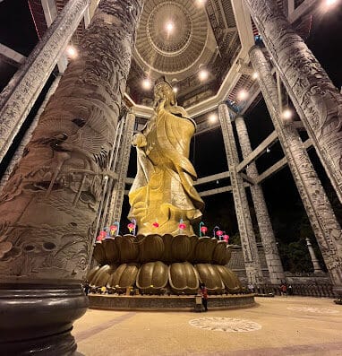 寺庙内矗立着一尊雄伟的金色佛像，周围环绕着巨大的大理石柱和精美的建筑细节，象征着宁静和精神意义。.