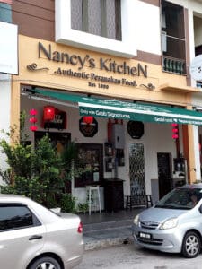 Bright and welcoming storefront of Nancy's Kitchen, a restaurant specializing in authentic Peranakan cuisine, offering a cozy dining experience since 1999 in a bustling urban area.