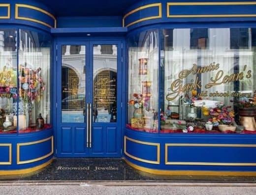 优雅的蓝色店面，配以金色点缀，展示着珠宝和鲜花。.