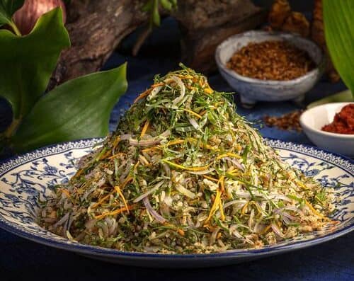 色彩鲜艳的混合香草沙拉，包含新鲜绿叶蔬菜、切丝蔬菜和香草，盛放在精美的餐盘中。是健康饮食和美味佳肴的理想之选。.