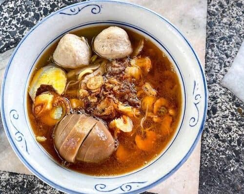 Delicious bowl of Vietnamese Pho featuring meatballs, beef, herbs, and flavorful broth served in a traditional ceramic bowl. Perfect for authentic Vietnamese cuisine lovers.