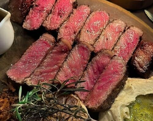 Delicious and juicy Wagyu beef cooked to perfection, showcasing a tender, marbled interior with a flavorful crust. A luxurious dining experience emphasizing high-quality meat and gourmet presentation.