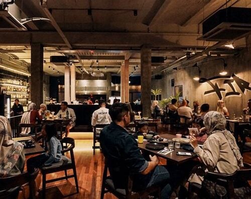 A lively restaurant interior with diverse patrons enjoying Asian cuisine, featuring warm lighting, contemporary decor, and casual dining atmosphere, perfect for food lovers seeking authentic Asian dishes.