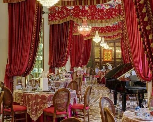 高分辨率图片展示了一家豪华的中餐厅，餐厅装饰着鲜艳的红色窗帘、华丽的吊灯和传统的金色装饰，营造出地道的用餐氛围。.