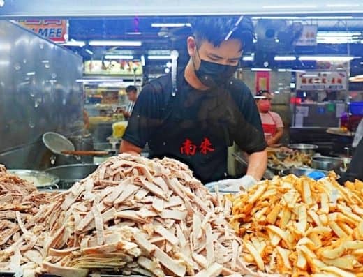 1. Fresh sliced meats and crispy fries at Onalulu popular Asian street food stall in a vibrant market setting.