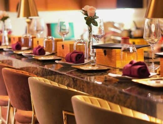 豪华的用餐布置，包括酒杯、紫色餐巾和花卉装饰，适合高档活动或私密晚宴。.