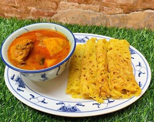 Delicious spicy curry served with golden crispy noodles on a stylish blue and white plate, perfect for authentic Asian cuisine enthusiasts.