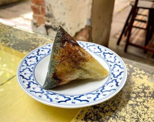 Delicious traditional Chinese sticky rice wrapped in bamboo leaves, served on a decorative blue and white plate, ideal for authentic Asian cuisine lovers.