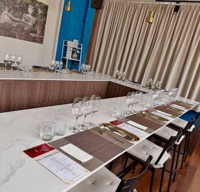 A stylish dining table at Onalulu restaurant featuring wine glasses, cutlery, and menus, perfect for a fine dining experience. The modern decor includes blue and beige accents, creating a welcoming ambiance.